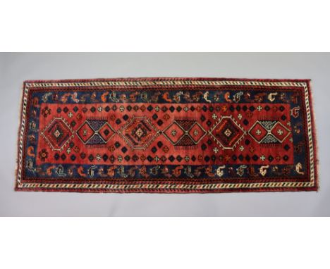 A Southwest Persian Qashqai runner of madder ground with repeating geometric floral &amp; animal designs surrounded by narrow