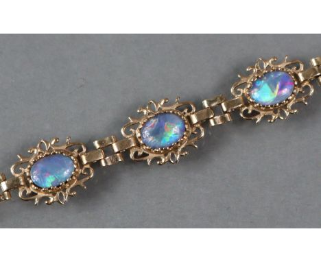An early 20th century 9ct. gold flexible bracelet set three oval opal doublets, 17.5cm long.  (3.7gm).