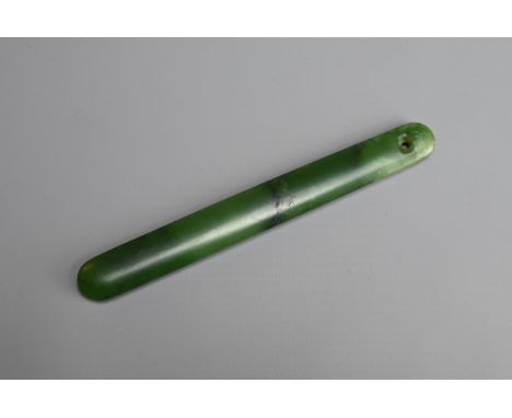 A CHINESE SPINACH JADE HAT PIECE OR FITTING, QING DYNASTY. Of flattened form with pierced hole to one end. 13cm length. In go