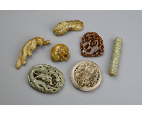 SEVEN CHINESE JADE CARVINGS. Comprising: a pierced pale jade circular pendant carved with a Guanyin, a pierced celadon jade o