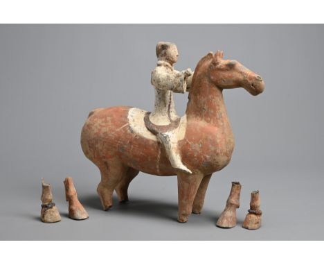 A CHINESE HAN DYNASTY GREY POTTERY PAINTED HORSE AND RIDER, 206 BC - 220 AD. The rider modelled seated astride the horse, wea