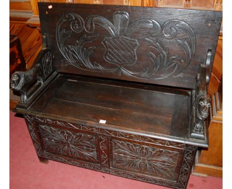 A circa 1900 line carved oak fold-over twin panelled monks' bench, having typical hinged boxseat base, with lion carved arm s