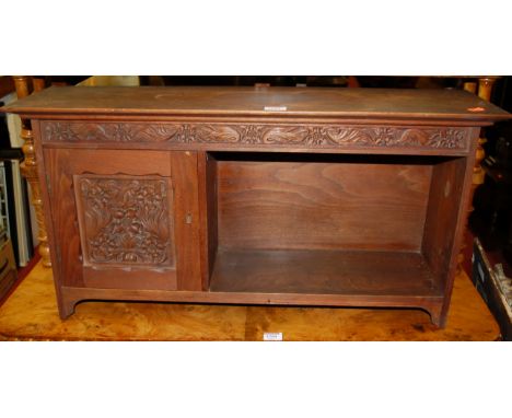 An early 20th century walnut relief carved hanging wall shelf, having single cupboard door and open compartment, width 74cm