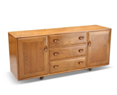 AN ERCOL LIGHT ELM SIDEBOARD, with a pair of cupboard doors flanking three drawers, moving on castors. 68cm high, 155.5cm wid