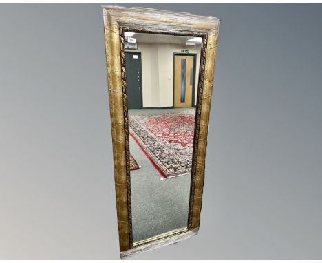 A contemporary mirror in a golden frame, 64cm by 158cm.