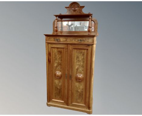 A 19th century Biedermeier mahogany and walnut double door cabinet fitted with two drawers and a mirror above.