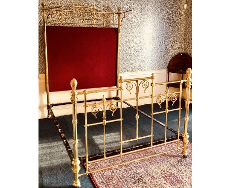 A Victorian brass tester bed, circa 1880, globe finials, turned posts, iron framed supports, red upholstered headboard, flora