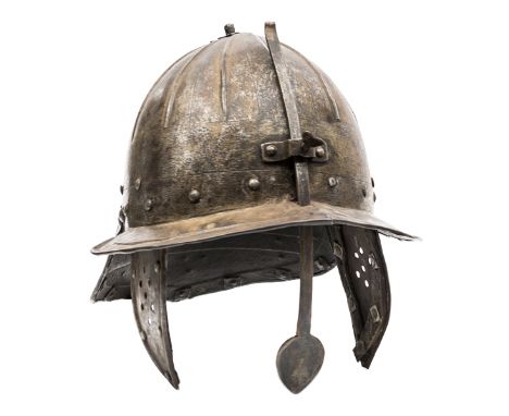 A 17th century “lobster tail” helmet, the ribbed skull formed in two parts, with integral peak, one side of which bears an in
