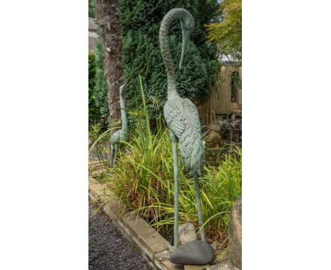 A pair of bronze figures of cranes one with head raised and the other lowered, both approx. 64in. (162.6cm.) high. (2)