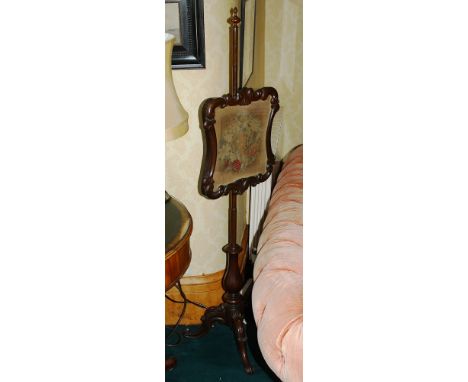 A William IV walnut pole screen the shaped scroll frame with petit point floral panel, on a turned baluster column and three 