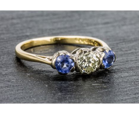 An antique 18ct gold, sapphire and diamond three stone ring the central brilliant cut diamond flanked by round cut cornflower