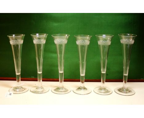 A set of six 1920s cut glass champagne flutes the drawn trumpet bowls with panel stem cutting and etched bands, on plain feet