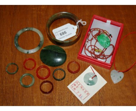 A Chinese apple green jade pendant carved as a ruyi fungi, together with a heart and disc shaped pendants in white and green 