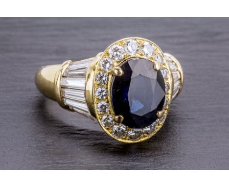 An 18ct yellow gold, sapphire and diamond cluster ring the oval cut sapphire within a border of sixteen graduated brilliant c