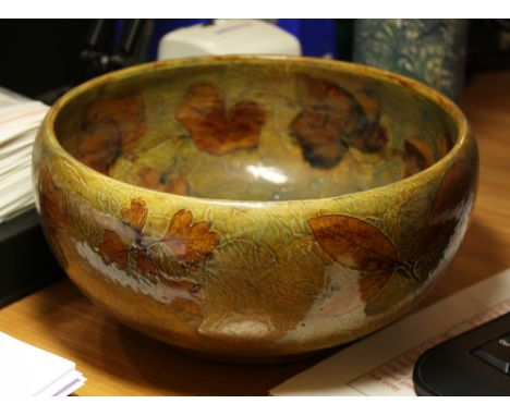 A Royal Doulton stoneware fruit bowl decorated with hawthorn, ivy and bay leaves on a mottled blue and light brown textured g