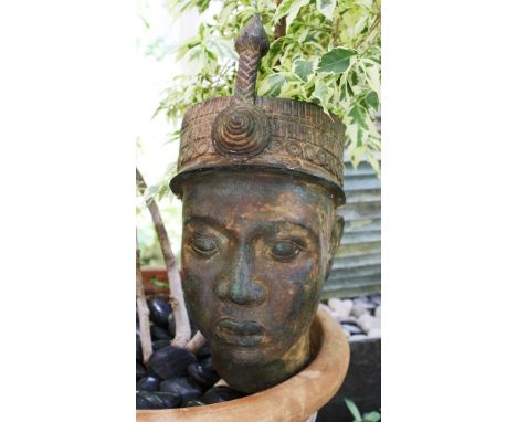 A hollow cast bronze head of an African youth 20th century, wearing a decorative hat with narrow brim and spear-like attachme