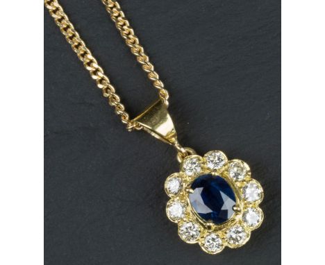 An 18ct yellow gold, sapphire and diamond cluster pendant the oval cut sapphire of good colour, within a scalloped border of 