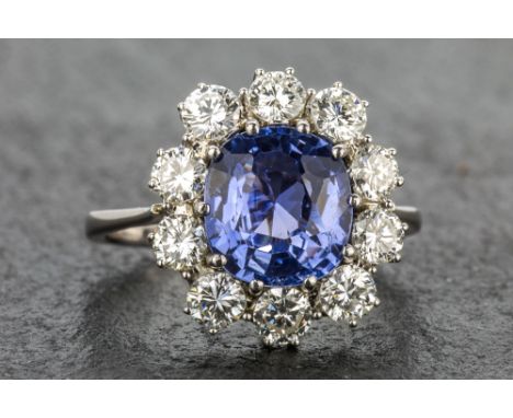 An 18ct white gold, unheated Ceylon sapphire and diamond cluster ring the 4 carat cushion cut sapphire of subtle pale blue co