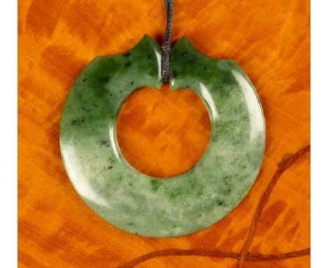 A Chinese carved jade disc pendant in graduated spinach to mottled dark celadon green jade, each side tapering to a shaped te