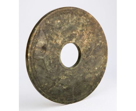 A large Chinese Han Dynasty style spinach and russet jade bi disc one side carved with four Taotie masks on a hatched ground,