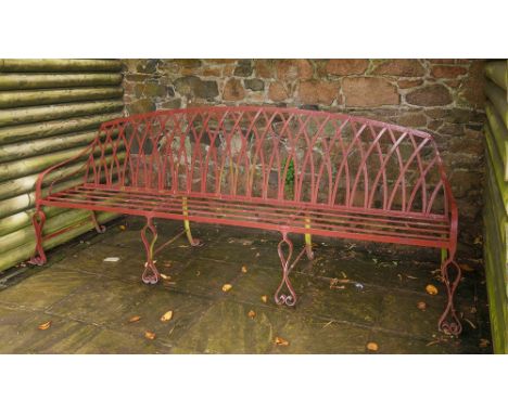 A wrought iron Georgian style three-seater garden bench with interlaced Gothic trellis back, on eight scroll-footed supports,