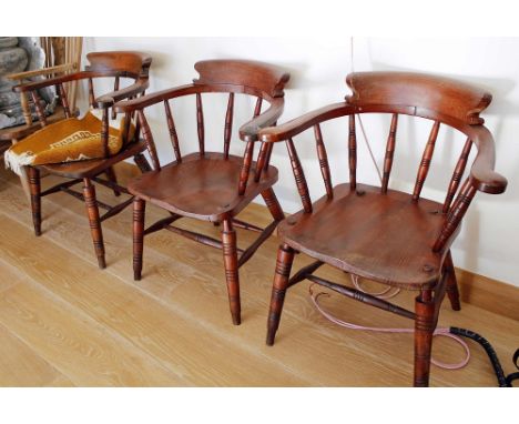 Three late 19th century captains' chairs with ring-turned spindle backs and conforming turned legs with ladder stretchers. (3
