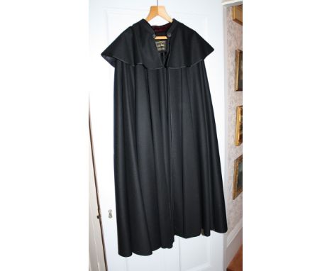 A fine quality Opera Cloak by Casa Seseña of Cruz 23, Madrid the heavy black material partially lined with plum velvet and wi
