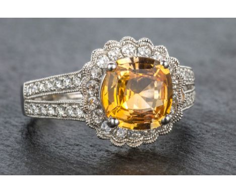 An 18ct white gold, yellow sapphire and diamond cluster ring the square cushion cut 2.11 carat sapphire within a scalloped mi