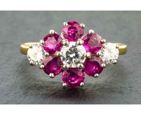 An 18ct gold, ruby and diamond floral cluster ring the six round cut rubies centred by a round brilliant cut diamond and flan