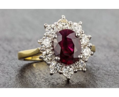 An 18ct white and yellow gold, Thai ruby and diamond cluster ring the oval cut 2.03 carat Thai ruby within a border of ten ro