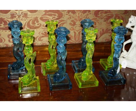 A set of eight Museum of Modern Art reproduction glass dolphin candlesticks comprising four in acid yellow and four in light 