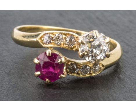 An 18ct yellow gold, ruby and diamond cross over ring set with a single 5mm. round cut ruby and a single approx. 0.5 carat ol