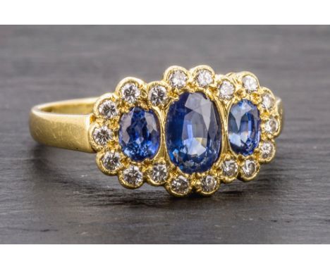 A Georgian style 18ct yellow gold, sapphire and diamond cluster ring with three graduated oval cut light blue sapphires withi