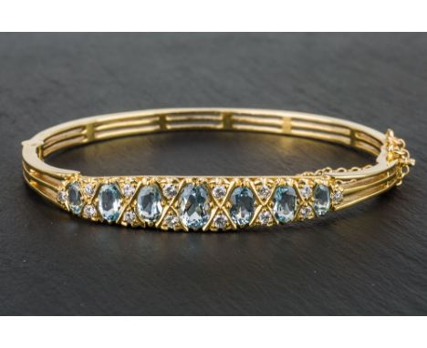 A 9ct yellow gold, aquamarine and diamond bangle London 1973, the three bar bangle set with seven graduated oval cut aquamari