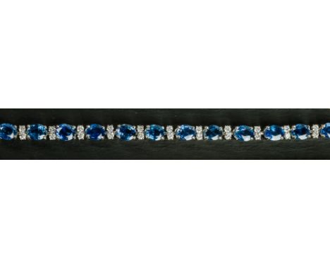 An 18ct white gold, sapphire and diamond bracelet set with nineteen oval cut sapphires, total weight 15.32 carats, alternatin