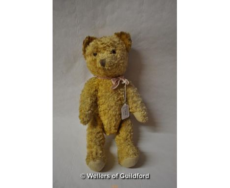 A vintage teddy bear with glass eyes, stitched nose and mouth, 37cm.