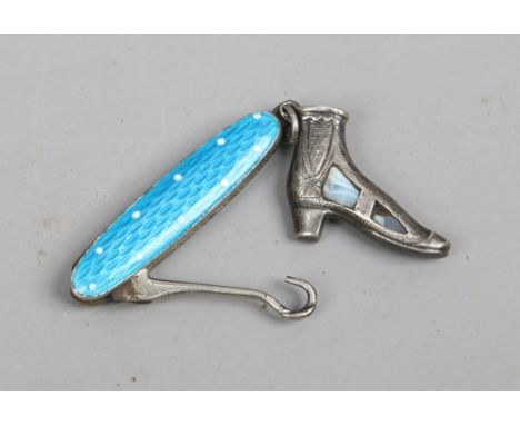 A folding button hook with engine turned and enamel handle along with a silver charm formed as a boot and set with hardstones