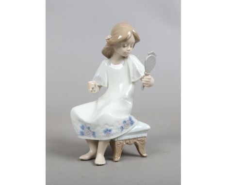 A Lladro figure of a young girl seated (AF).
