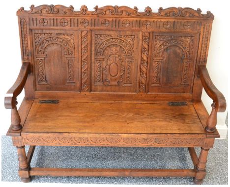 Late Victorian carved oak hall bench with carved top rail above three fielded panels, with hinged seat below and a lunette ca
