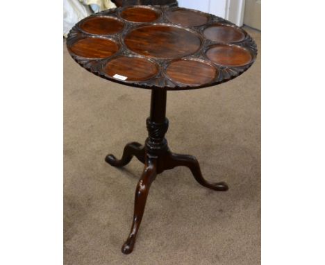 A carved mahogany tripod table, in George II style, the circular top with a moulded dished centre centred by eight smaller mo