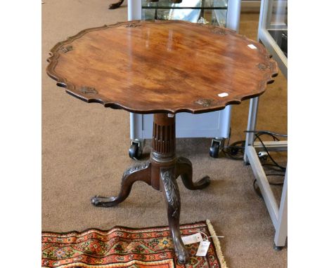 ^ A George III mahogany tripod table, the moulded top raised on a stop-fluted column support, with acanthus carved cabriole l