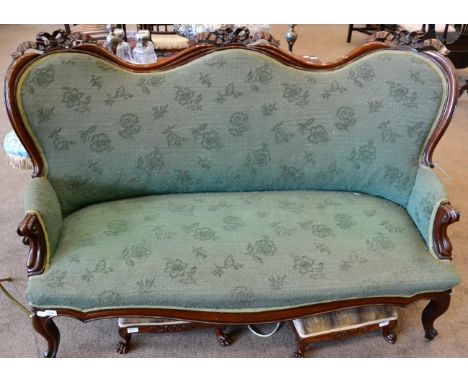 A Victorian carved mahogany two-seater sofa, upholstered in green floral moquette, with a moulded frame and ribbon tied top r