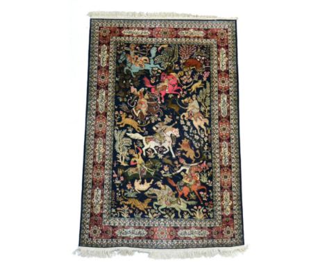 Kashmir silk rug, North west India the indigo field of hunting scene enclosed by coral pink cartouch borders of stylised text