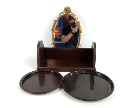 A brown bakelite book trough, two circular trays and a gilt framed easel backed mirror.