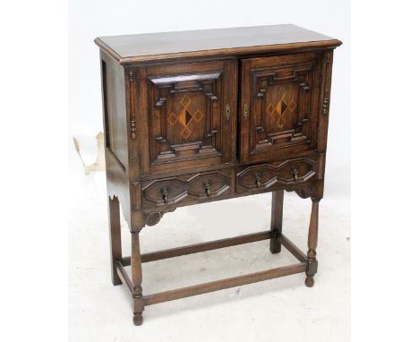 An inlaid oak cupboard of two doors enclosing single shelf over two short drawers, 115 x 91 x 40cm. CONDITION REPORT: General