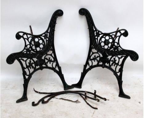 A pair of pierced cast iron garden bench ends with scrolling arms (supports present for underneath slats but no slats).