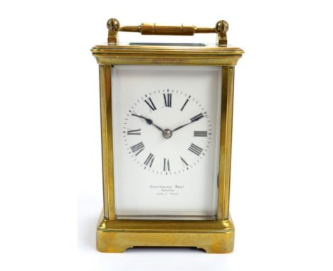 A late 19th century brass carriage clock with swing loop handle above rectangular white enamel dial set with Roman numerals, 