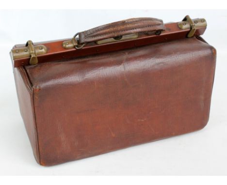 An Edwardian brown leather doctor's bag containing an assortment of vintage medical/surgical instruments, length 41cm.