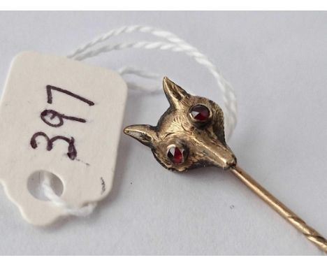 A gold fox head stick pin with red stone eyes