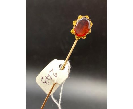 A large flat cut hessonite garnet stick pin